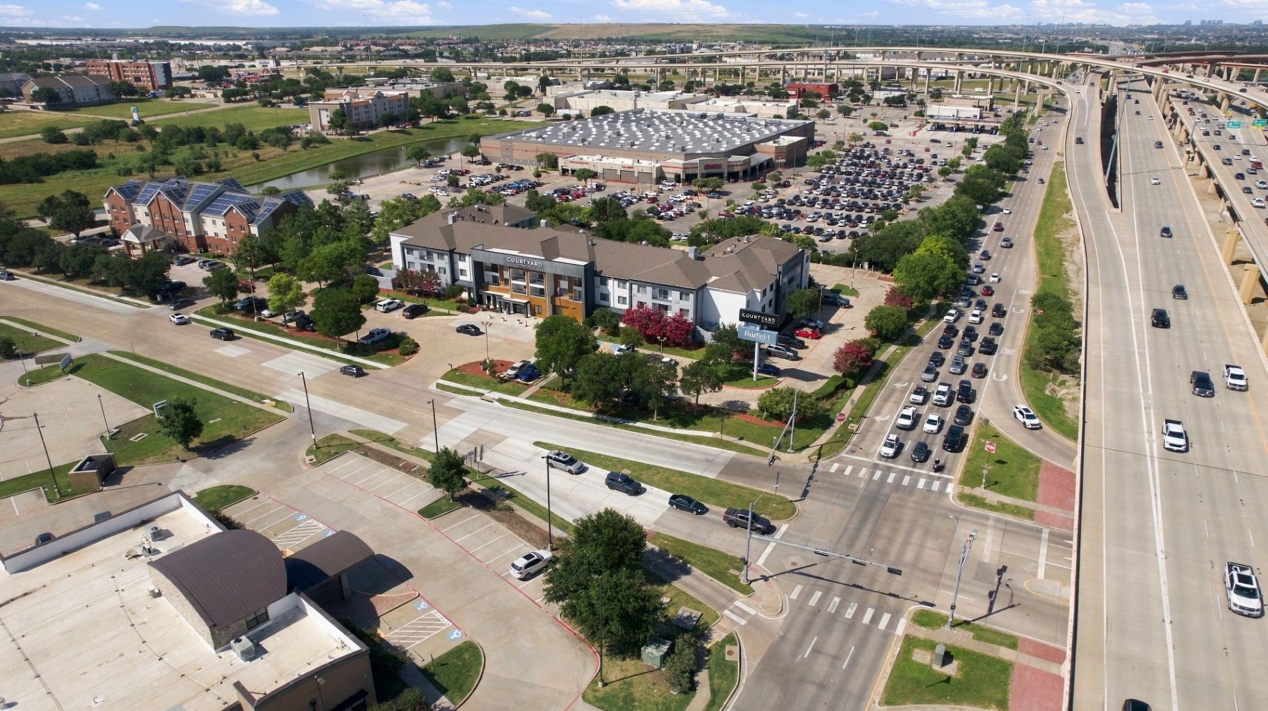 Aerial commercial property documentation showing a multi-building development, parking, roads, and highway access.